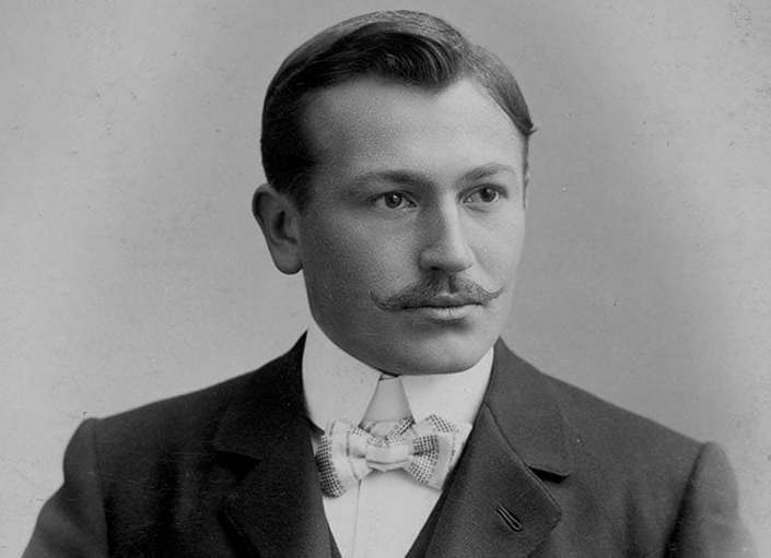 Black and white portrait of Hans Wilsdorf in formal attire with a bow tie against a plain background
