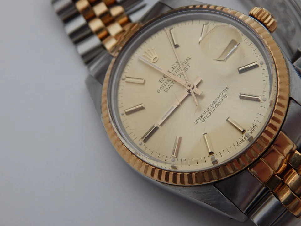 Close-up of a gold and silver Oyster Perpetual Datejust watch with a detailed face on a light background