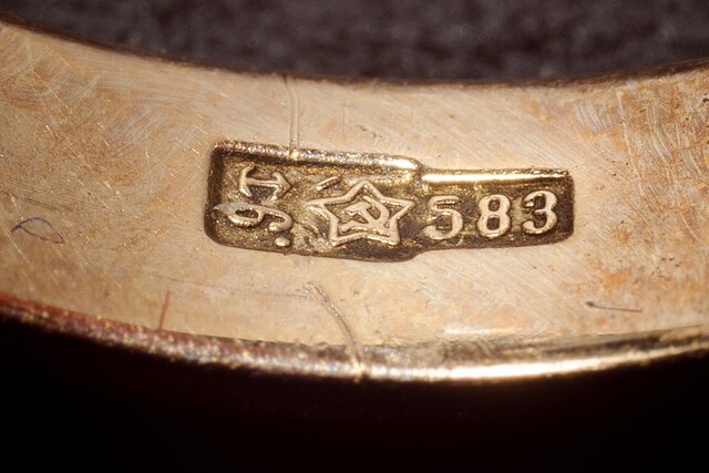 Gold ring with '583' hallmark on a dark background