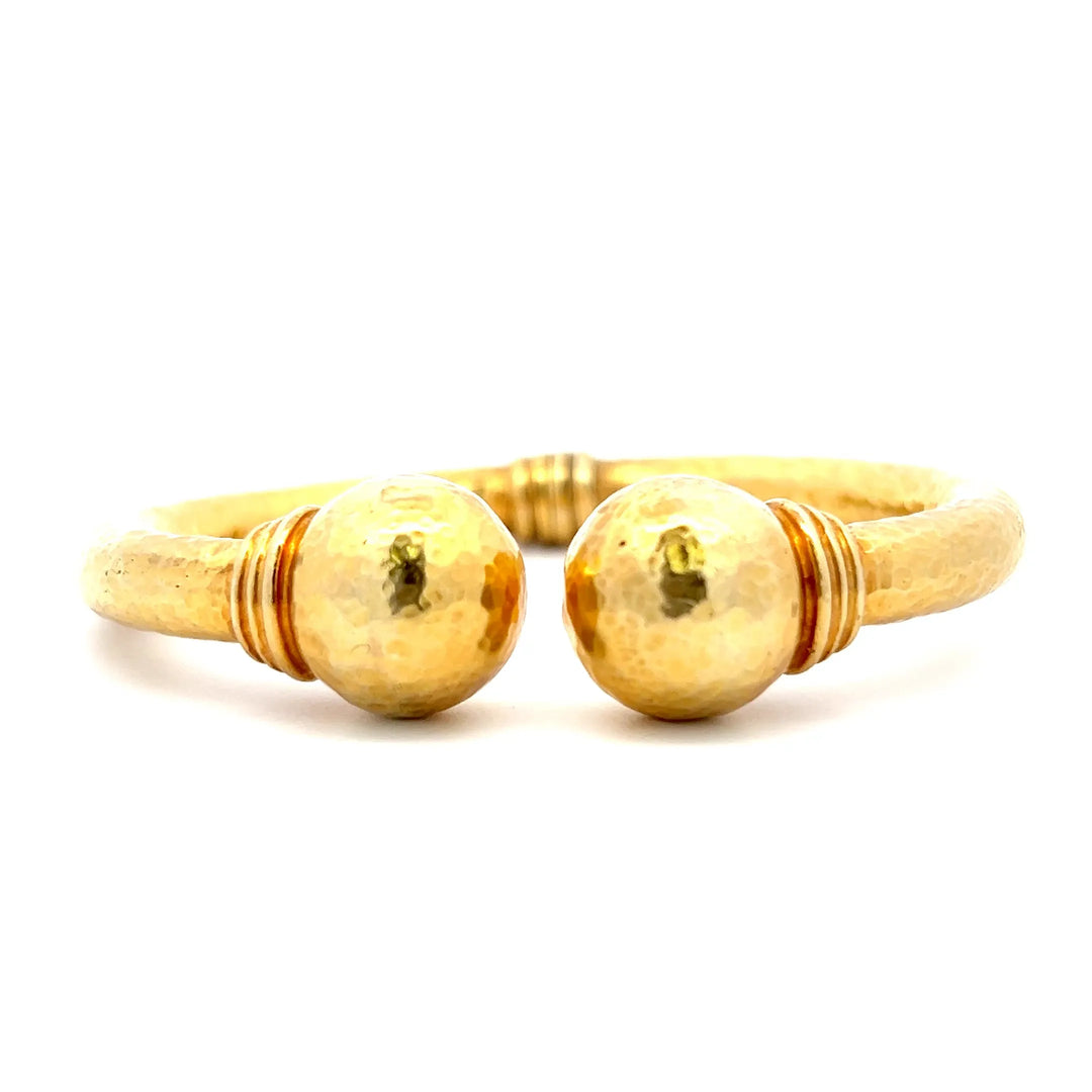 An estate 18 karat yellow gold cuff bracelet with round finials and a hammered texture.