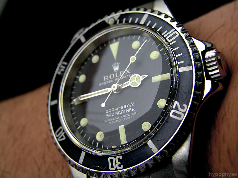Rolex Submariner watch with black dial and silver case on a person's wrist.