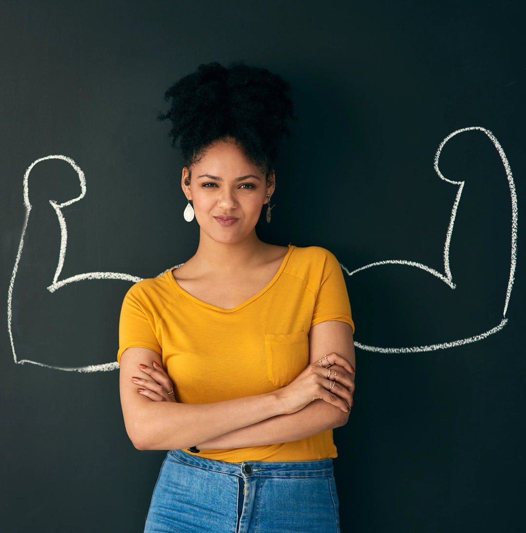 An image of a confident-looking woman in front of a chalk with muscular arms drawn to symbolize her strength