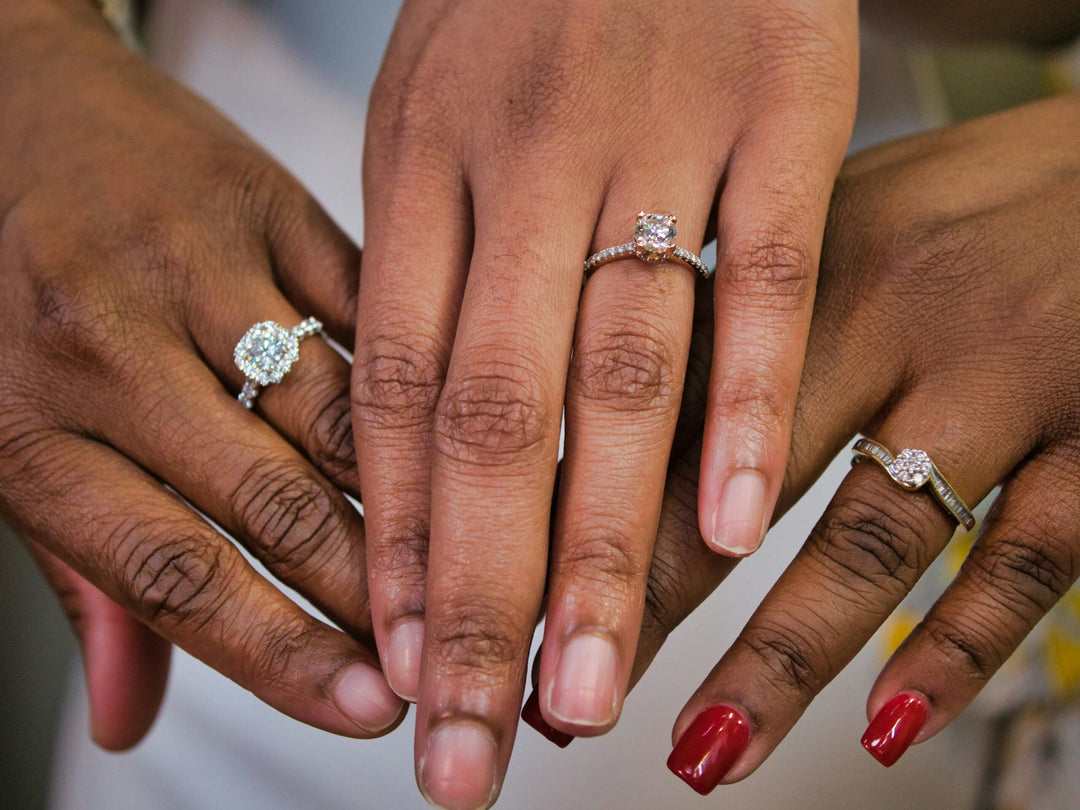 Three hands each with a different style of diamond engagement ring