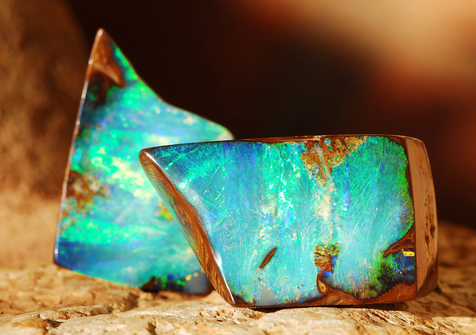 Two pieces of boulder opal with vibrant colors on a textured surface