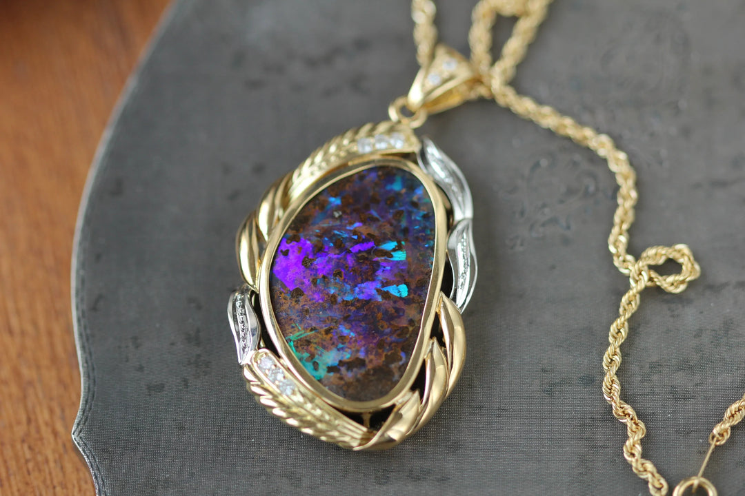 A black opal pendant necklace in in 14 karat yellow gold with white gold and diamond accents.