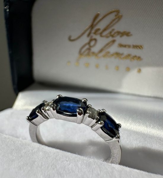 A custom design finished product of a blue sapphire and diamond band inside a Nelson Coleman Jewelers jewelry box