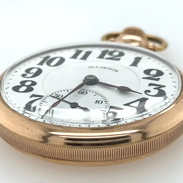 An antique pocket watch with gold-tone metal, a white face, and black hands and indices