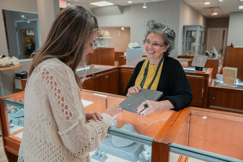 Inside the Frederick jewelry store a smiling and helpful associate shows a shopper a beautiful necklace on the countertop