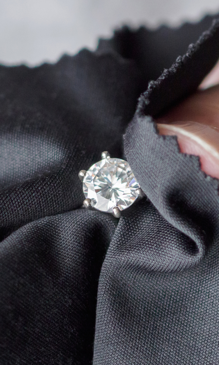 A close-up image of a diamond ring being gently cleaned in a black cloth