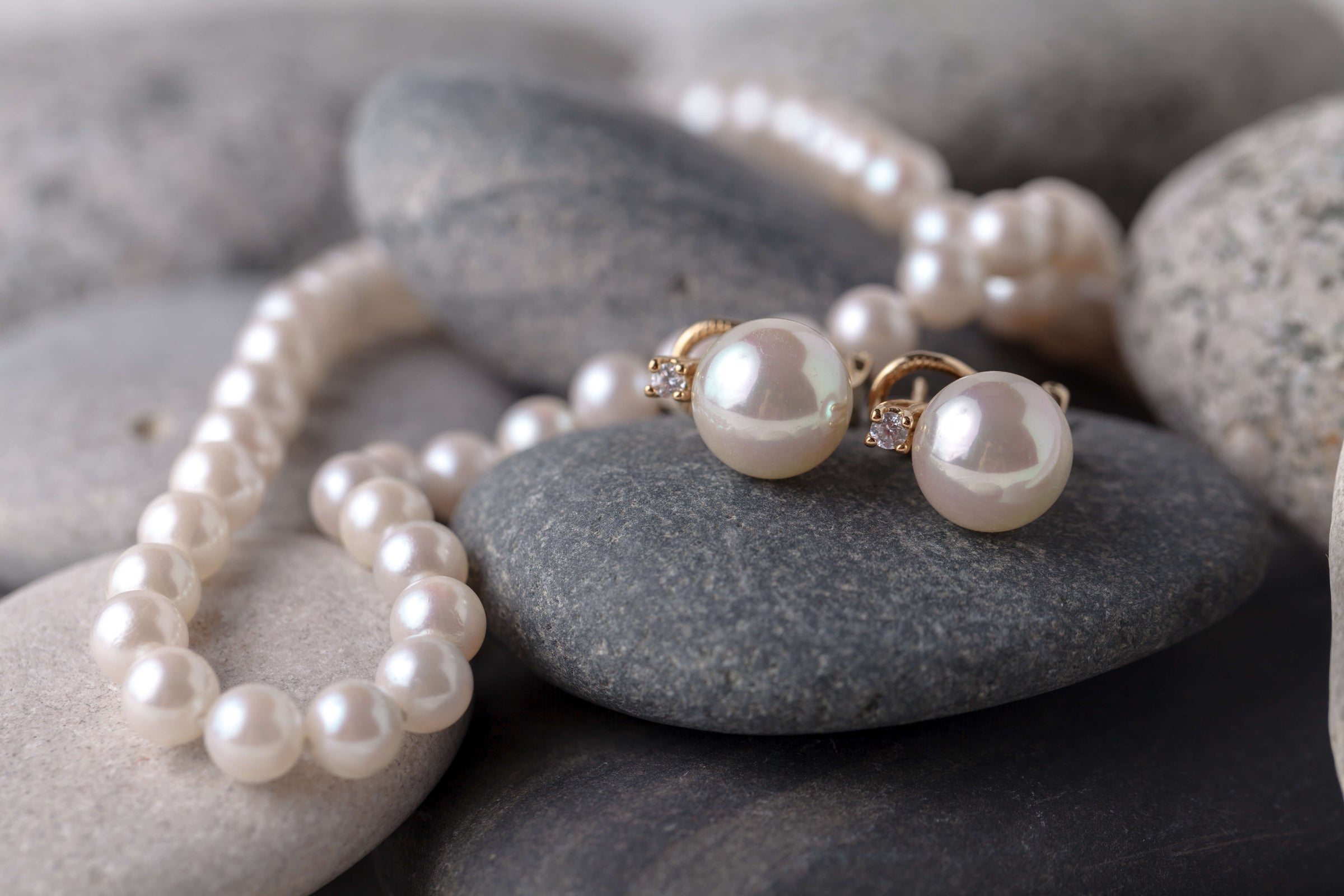 Pearl necklace and earrings on gray stones