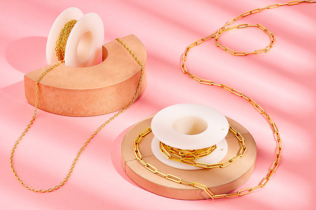 Gold chain and white ceramic donut-shaped objects on a pink background