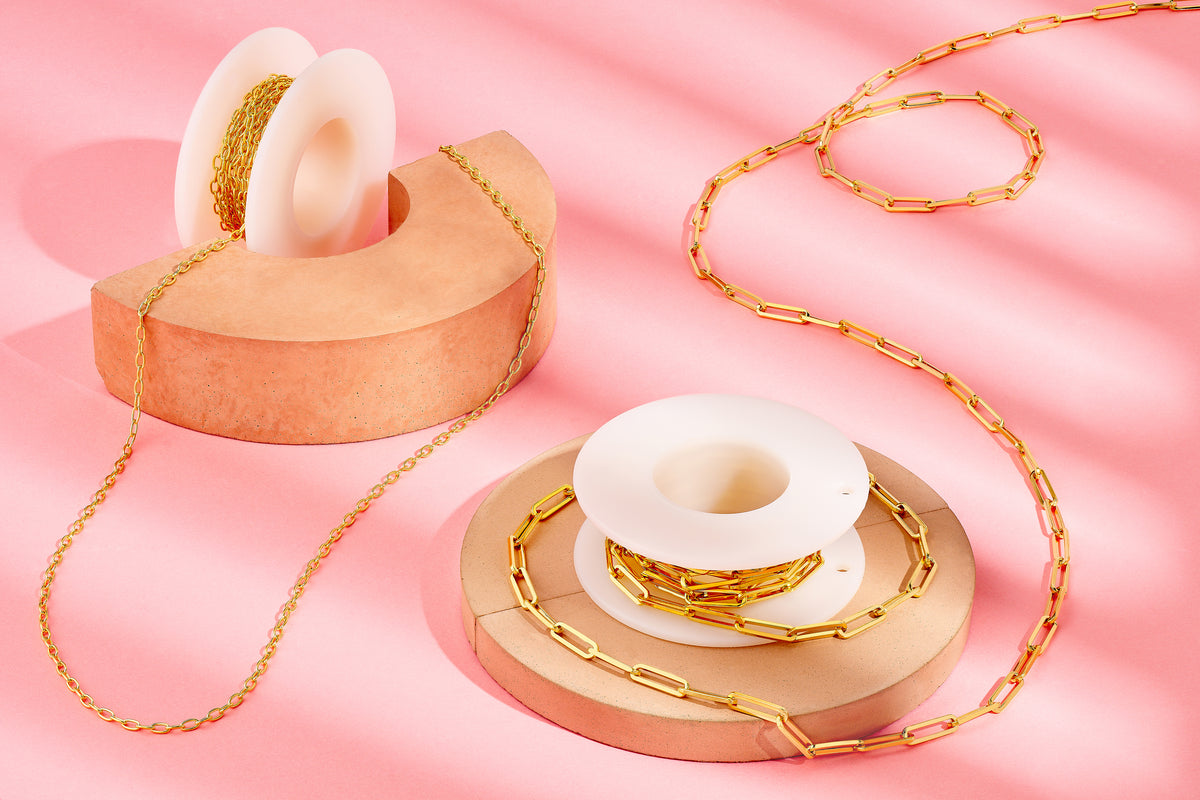 Gold chain and white ceramic donut-shaped objects on a pink background