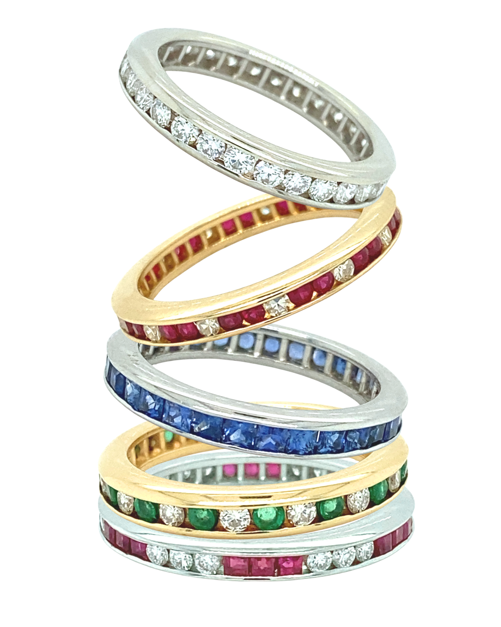 A stack of eternity channel wedding bands including diamond, blue sapphire, ruby and diamond, and emerald and diamond.