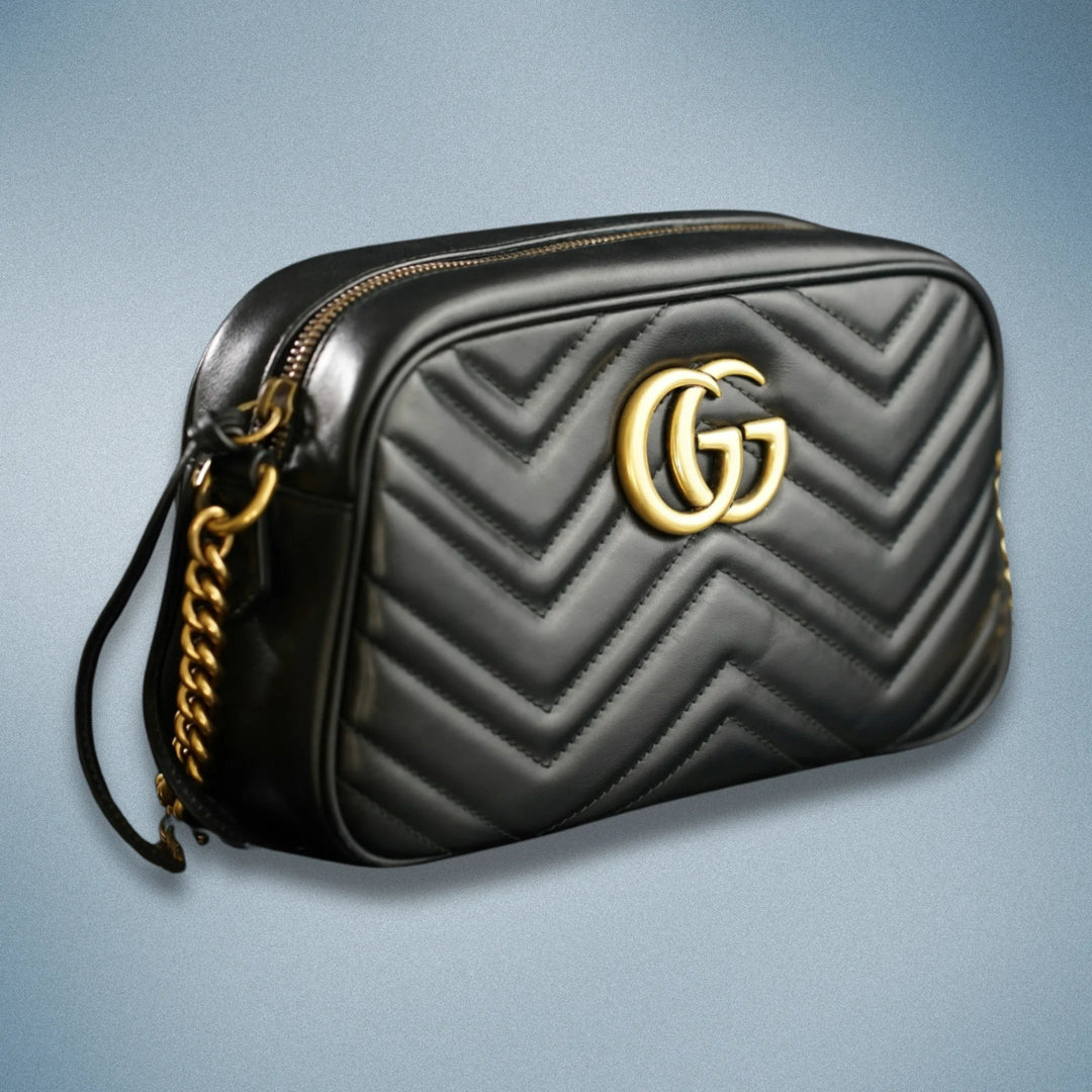 A black leather Gucci brand handbag with gold-tone brand logo and accents