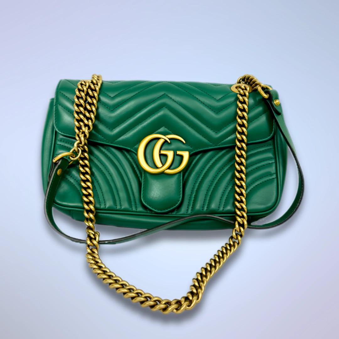 A green leather vintage luxury handbag with gold-tone accents and a gold-toned chain shoulder strap