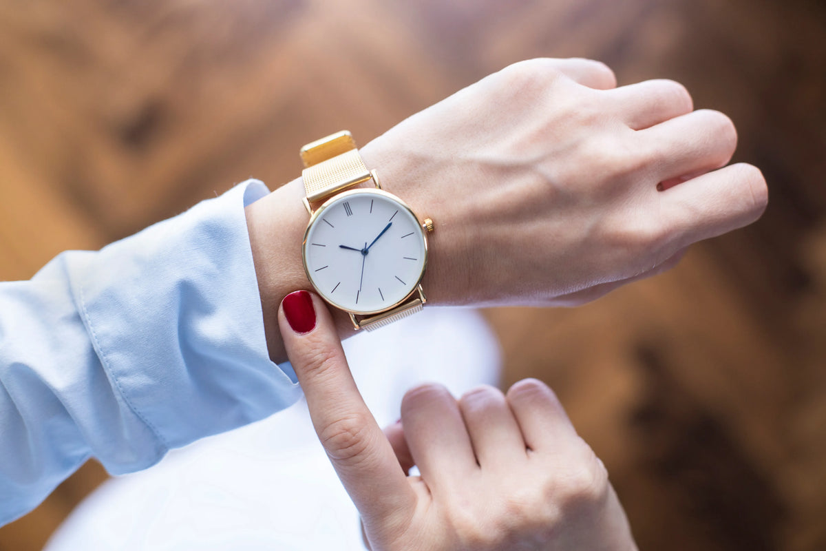 Person wearing a gold watch with a blurred background