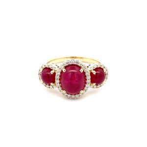 One 14 karat yellow gold LoveFire Greenland ruby and diamond ring by Tache containing a center 9x7mm oval cabochon ruby and 2 side 5mm round cabochon rubies with all 3 rubies weighing 3.95 carats total weight. Each ruby is surrounded by a diamond halo.