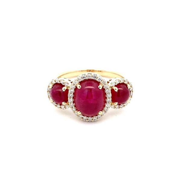 One 14 karat yellow gold LoveFire Greenland ruby and diamond ring by Tache containing a center 9x7mm oval cabochon ruby and 2 side 5mm round cabochon rubies with all 3 rubies weighing 3.95 carats total weight. Each ruby is surrounded by a diamond halo.