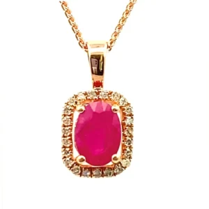 one 14 karat rose gold pendant necklace featuring one 7x5mm oval-shaped brilliant-faceted ruby weighing 0.90ctw in a four-prong setting surrounded by an elongated cushion-shaped halo of round-faceted diamonds. The pendant features a traditional-style polished bail and is suspended from a 14 karat rose gold chain.