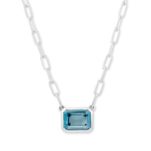 A sterling silver solitaire necklace with an emerald-cut blue topaz in an east-west bezel setting fixed on a paperclip chain