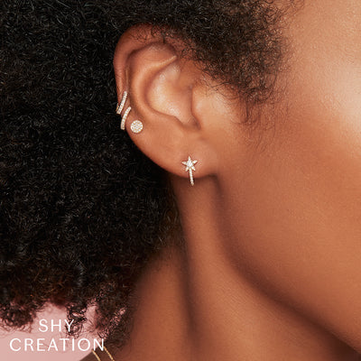 a model wearing a pair of 14 karat white gold disc stud earrings pave set with single-cut diamonds weighing 0.07 carat total weight stacked with other earrings