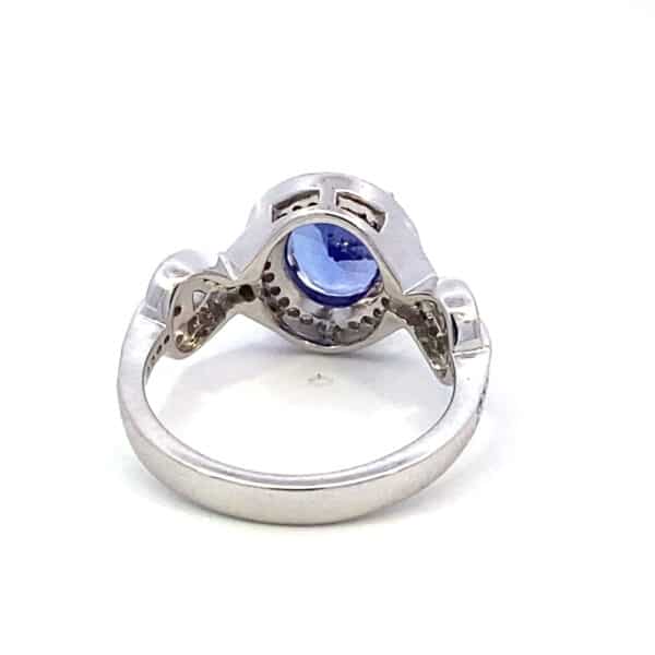 A 14 karat white gold ring by Lali with a center oval faceted tanzanite measuring 9x7mm and round diamonds set in the halo and in a partial figure-eight twist design in the band