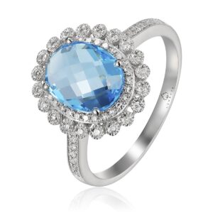 A 14 karat white gold fashion ring by Luvente with a center oval-shaped checkerboard-faceted blue topaz weighing 2.78 carats and 0.18 carats of round diamonds set in a double halo with a floral motif and in the shoulders of the band