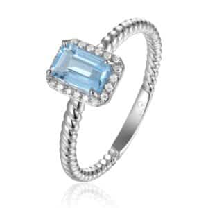 A white gold ring with a rope style shank and an emerald-cut blue topaz with a diamond halo