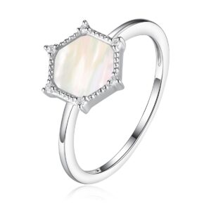 A white gold ring featuring a mother-of-pearl center with a hexagon halo set with diamonds at each point