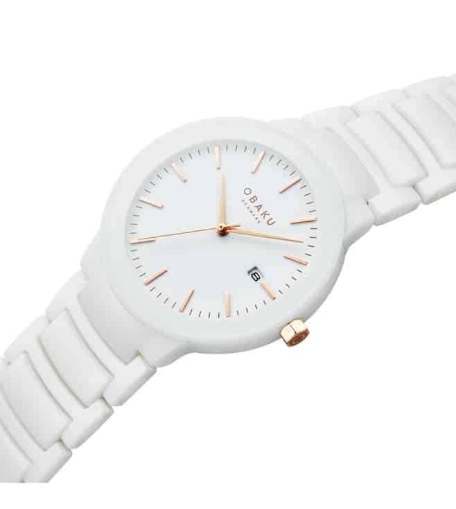the Pil Lille Milk watch by Obaku. The watch features a 38mm white ceramic case with a white dial and white ceramic bracelet links. The watch also features IP rose gold crown, three-hand movement, hour and minute markers, and butterfly buckle. The case features a sapphire crystal. There is a date window at the 3 o'clock location.