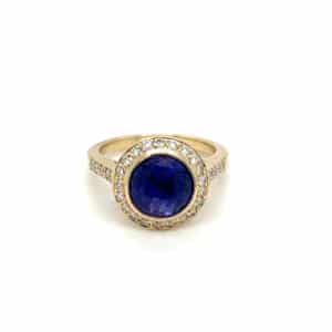 An estate 14 karat yellow gold halo ring with a center round blue-purple sapphire in a bezel setting with diamonds set in the halo and the band