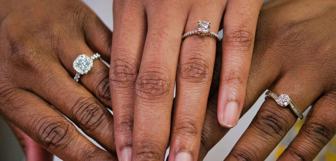 Three hands each with a different style of diamond engagement ring