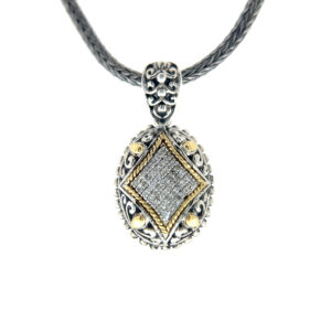 An estate sterling silver oval pendant necklace with diamonds and 18 karat yellow gold accents on a tulang naga chain