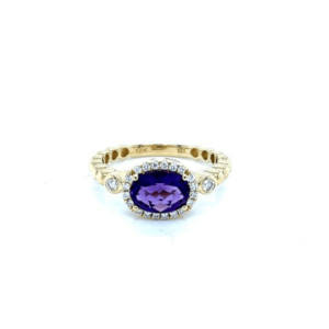 One 14 karat yellow gold fashion band with an oval-faceted amethyst in an east-west prong setting with a diamond halo and a diamond in each shoulder with a bubble style band