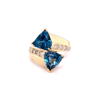 One estate 14 karat yellow gold bypass ring with 2 trillion-cut blue topazes and 10 round brilliant accent diamonds