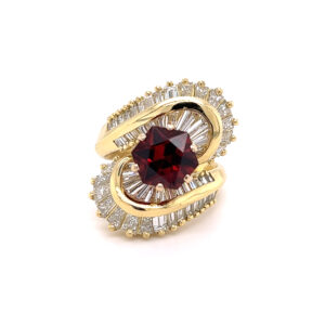 One estate 18 karat yellow gold ballerina ring with a center hexagon-shaped faceted almandine garnet and a diamond halo with 58 baguette diamonds