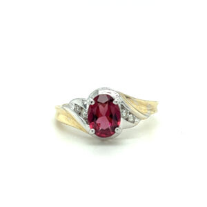 An estate 14 karat two-tone gold ring with an oval rhodolite garnet and diamond accents