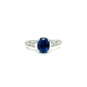 An estate vintage-inspired 18 karat white gold ring with an oval blue sapphire and diamond accents