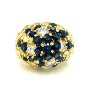 A stunning Estate Blue Sapphire and Diamond Dome Ring crafted from 18 karat yellow gold. The ring features 2 carats of round blue sapphires and 0.70 carats of round brilliant diamonds. The gold band has an organic nature motif resembling flowers or plants on the shoulders.