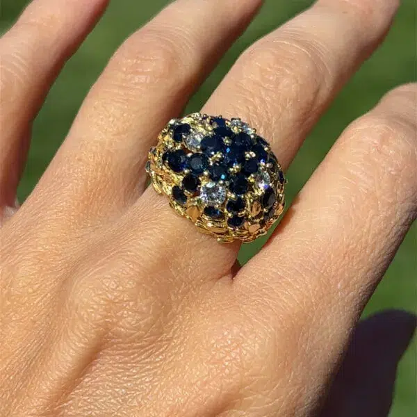 A stunning Estate Blue Sapphire and Diamond Dome Ring crafted from 18 karat yellow gold. The ring features 2 carats of round blue sapphires and 0.70 carats of round brilliant diamonds. The gold band has an organic nature motif resembling flowers or plants on the shoulders.