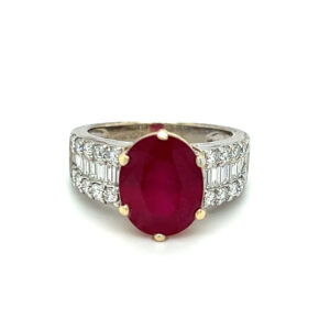 One estate 18 karat two-tone gold ring with an oval-faceted ruby and three rows of diamonds in the bands