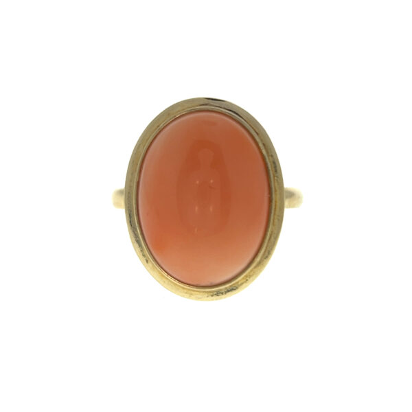 One estate vintage 14 karat yellow gold solitaire ring with an oval cabochon salmon pink coral in a bezel setting