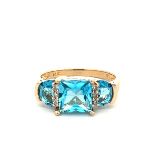 An estate 14 karat yellow gold three-stone ring with a princess cut blue topaz, 2 half moon-cut blue topazes, and 6 accent diamonds