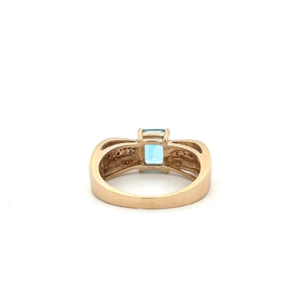 An estate 14 karat two-tone gold fashion ring with an emerald-cut blue topaz and diamond accents in the band