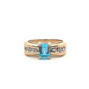 An estate 14 karat two-tone gold fashion ring with an emerald-cut blue topaz and diamond accents in the band