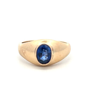 An estate vintage 14 karat yellow gold solitaire ring featuring an oval-shaped faceted blue sapphire in a bezel setting
