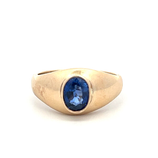 An estate vintage 14 karat yellow gold solitaire ring featuring an oval-shaped faceted blue sapphire in a bezel setting