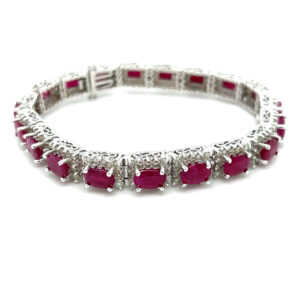 An estate 18 karat white gold line bracelet set with oval pink rubies with diamond halos