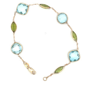 An estate 14 karat yellow gold link bracelet with 4 blue topazes and 4 peridots in an alternating pattern