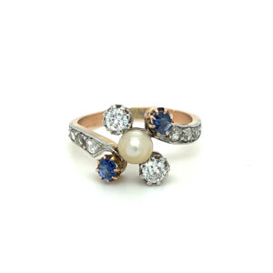 An estate vintage platinum and 18 karat rose gold bypass ring with a pearl center and blue sapphire and diamond accents